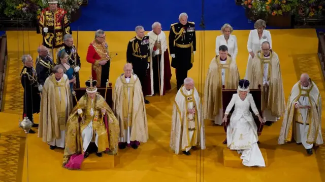 Charles and Camilla sit with crowns on their heads