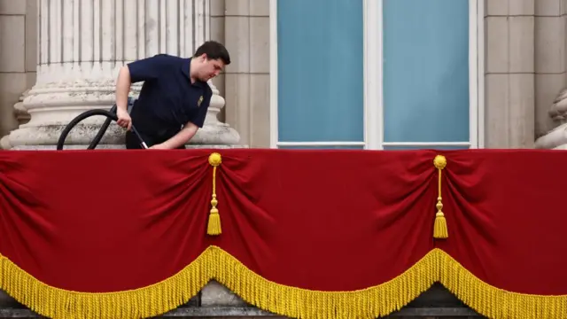 A man vacuums the balcony of Buckingham Palace