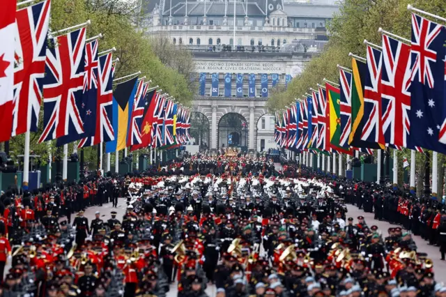 Thousands of armed forces personnel walk along The Mall