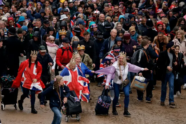 People run towards the Buckingham Palace balcony from Trafalgar Square following the coronation ceremony of Britain's King Charles and Queen Camilla