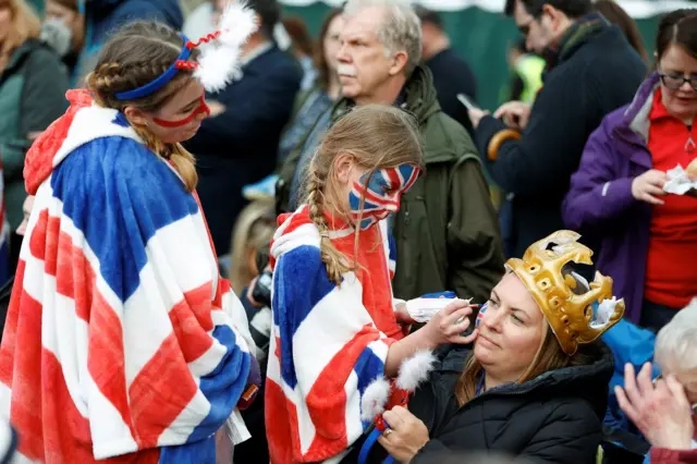 A kid paints a union flag on an adult's face