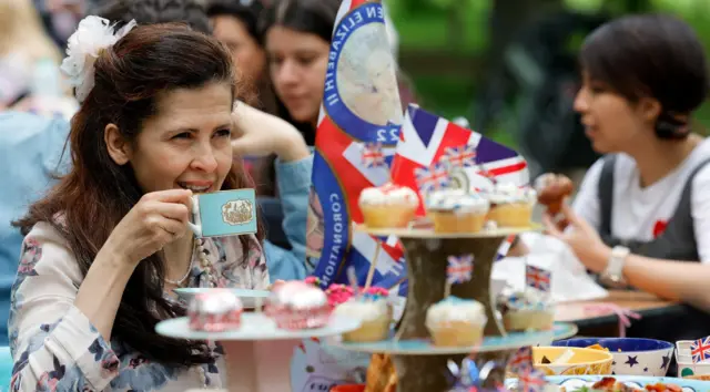 A woman looks on as people celebrate Britain's King Charles' coronation with the Big Lunch at Regent's Park, in London, Britain, May 7, 2023.