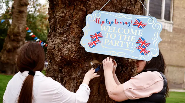 Two women set up decorations for a party in St James Church to celebrate the coronation