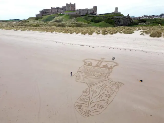 Aerial view of a giant portrait of King Charles III drawn in wet sand