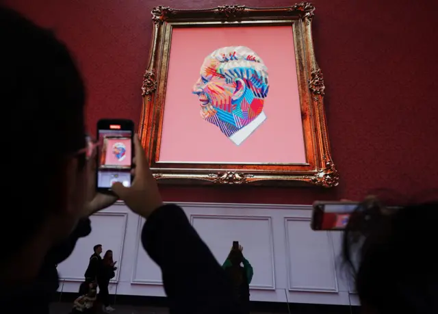 People take photos of a portrait of King Charles III