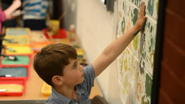 Prince Louis uses his hand to make a paint decorations on a wall