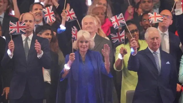 The Prince of Wales (L), the Queen and the King (R) wave flags at the concert on Sunday