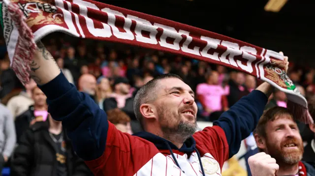 Northampton fan raises his scarf in the stands