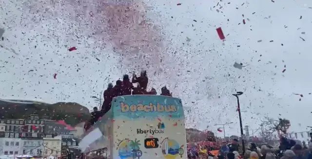 Confetti in the air as a crowd watch a bus go past