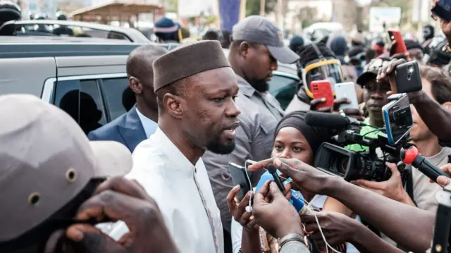 Ouasmane Sonko speaks to journalists while his convoy stops on the way to his trial in Dakar on March 16, 2023.