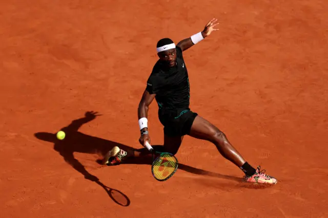 Frances Tiafoe slides to hit the ball