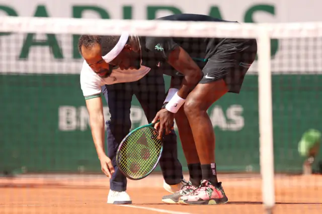 Frances Tiafoe and umpire Kader Nouni debate whether a ball mark is in or out on the court.