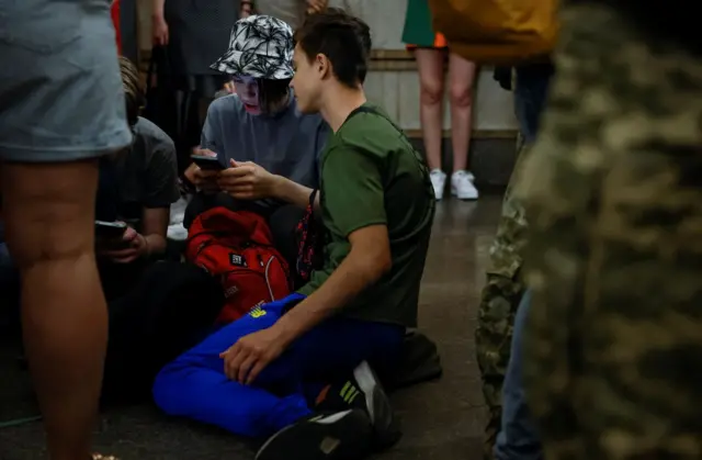 Boys play on a phone, as they hide with other local residents inside a subway station during an air raid alert, amid Russia's attack on Ukraine, in Kyiv, Ukraine, June 1, 2023