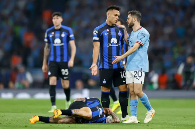 Lautaro Martinez remonstrates with Bernardo Silva as Federico Dimarco lays on the floor