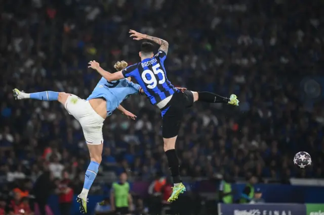 Erling Haaland and Alessandro Bastoni challenge for the ball in the air