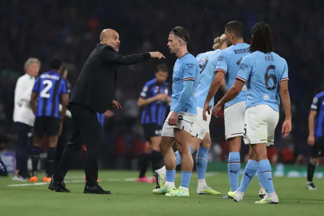 Pep Guardiola (left) speaks to his Man City players, including Jack Grealish