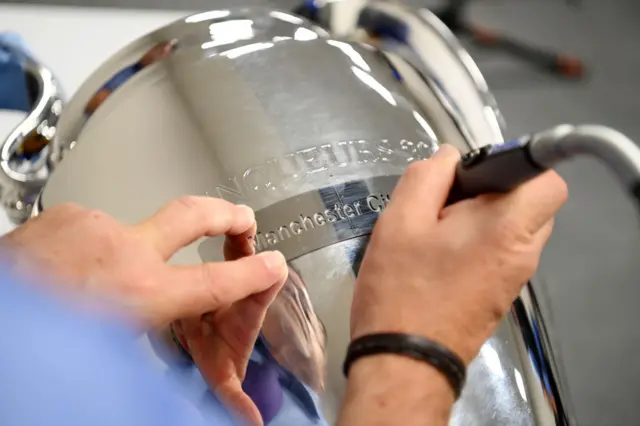 Engraver etches Manchester City's name on the trophy