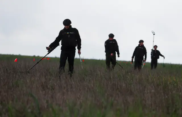 Ukrainian security forces inspect the recaptured area for mines and unexploded shells