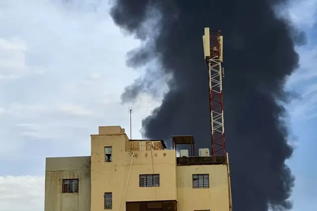 Black smoke billows behind buildings amid ongoing fighting in Khartoum on June 9, 2023