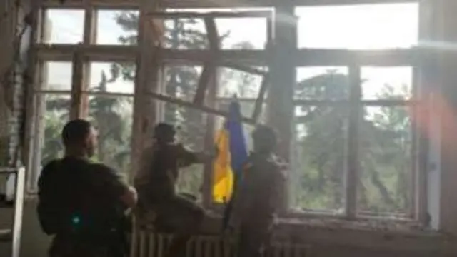 Ukrainian soldiers place their flag on a building in Blahodatne - one of three villages Ukraine says it has recaptured from Russia