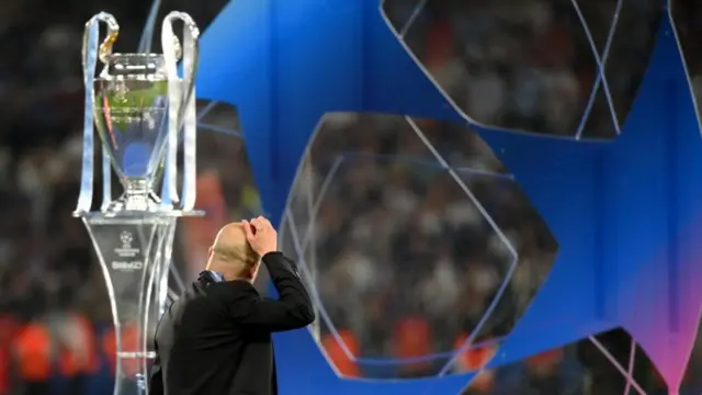 Pep Guardiola next to the Champions League trophy