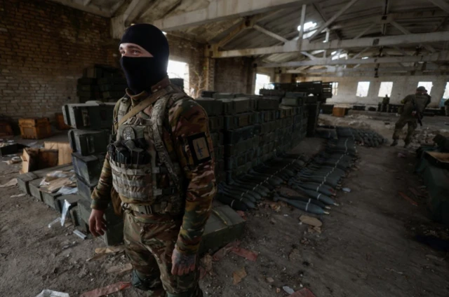 A Ukrainian soldier stands inside a building filled with ammunition