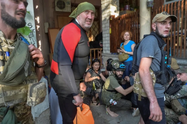 Rescuers, servicemen and volunteers react during a Russian shelling