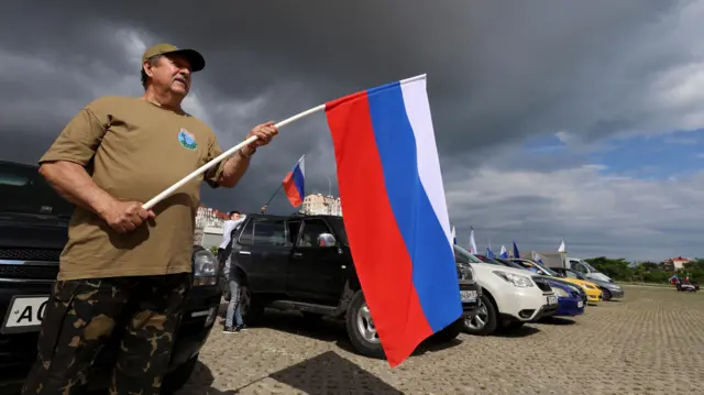 Participants attach flags to their cars before an automobile rally marking Russia Day in Sevastopol, Crimea