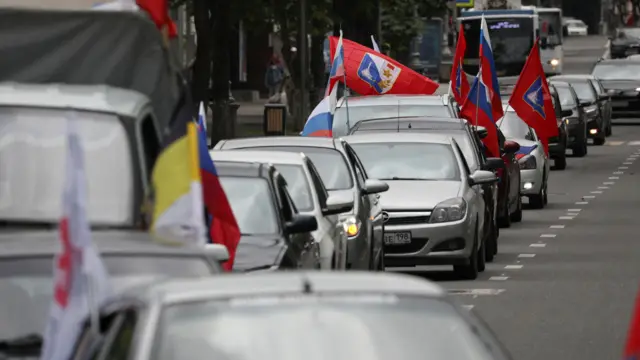 A row of cars with Russian flags attached