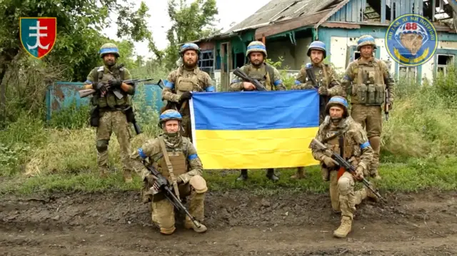 Ukrainian servicemen raise up their national flag in Storozheve