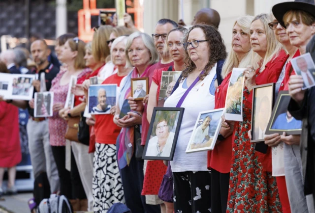 People hold pictures of loved ones lost during the pandemic outside the UK Covid-19 Inquiry at Dorland House in London.