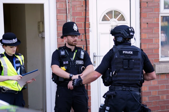 A police officer speaks with armed police at an address on Ilkeston Road in Nottingham