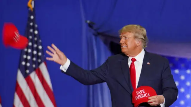 Former U.S. President Donald Trump throws a Save America cap as he attends a rally in Warren, Michigan