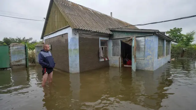 A man standing in flood water outside a building