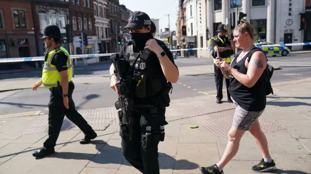 A police officer, armed with a large gun, walks through Nottingham City Centre