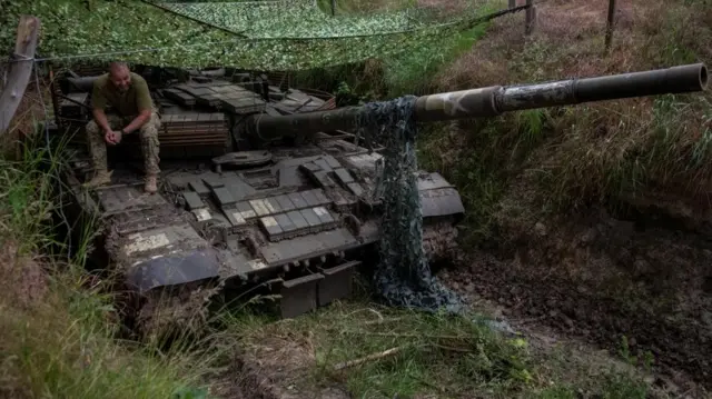 A Ukrainian serviceman sits on a tank