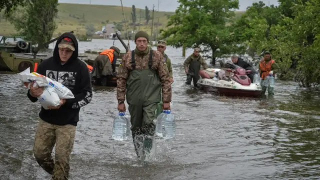 Ukrainian servicemen unload humanitarian aid for local residents after the Nova Kakhovka dam breached, in the flooded village of Afanasiivka