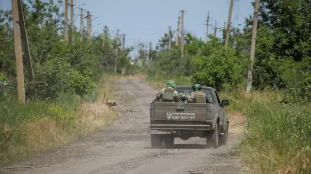 Ukrainian service members ride a military vehicle in Neskuchne