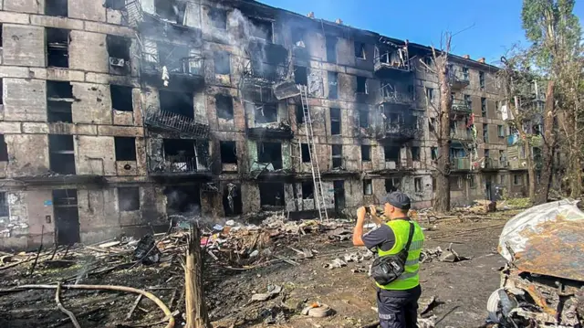 A man standing in front of a damaged building in Kryvyi Rih