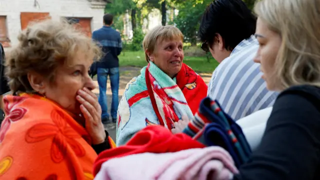 People react at a site of a residential building heavily damaged by a Russian missile strike