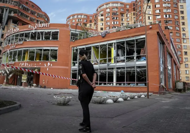 A police officer stands next to a shopping mall damaged by a Russian missile strike, amid Russia's attack on Ukraine, in Odesa