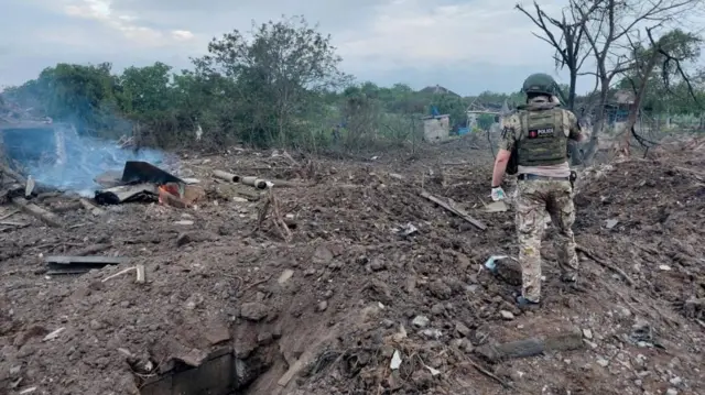 A police officer inspects a residential area hit by a Russian missile strike in Kostiantynivka