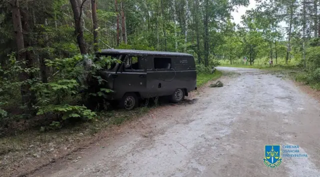 A vehicle marked with bullet holes stands at a roadside