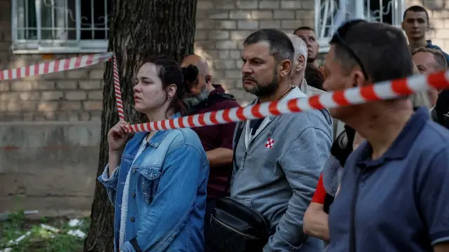 Civilians gather behind an emergency cordon