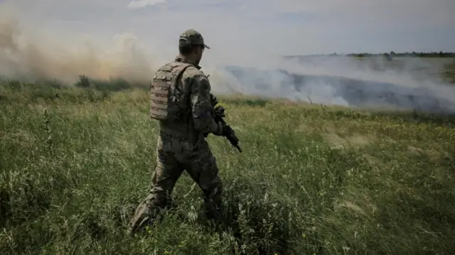 A Ukrainian serviceman walks through a field