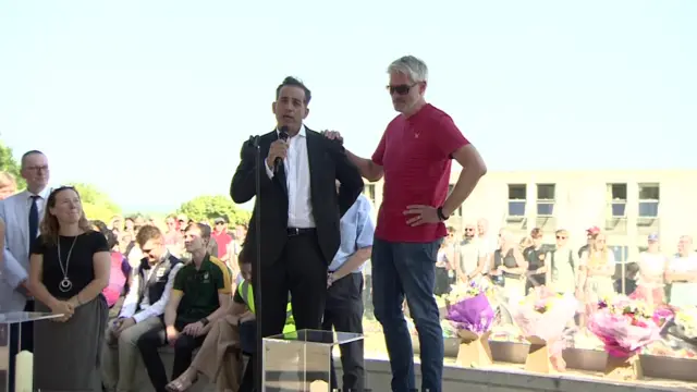 Grace's dad speaks at the vigil, with Barnaby's dad putting his hand on his shoulder