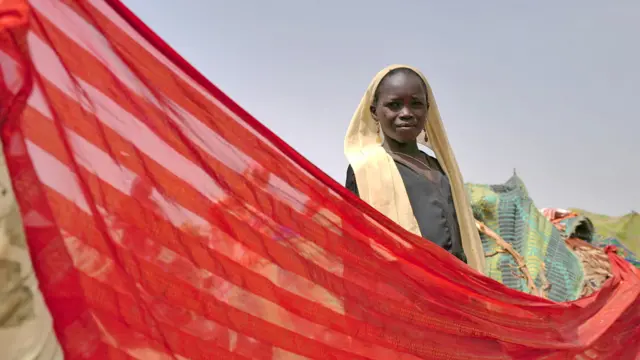 A Sudanese girl who fled the conflict in Sudan's Darfur region, and was previously internally displaced in Sudan, stands at her makeshift shelter near the border between Sudan and Chad, while taking refuge in Borota, Chad - 13 May 2023