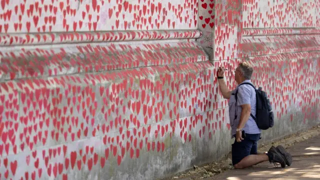 A man draws on the National Covid Memorial Wall in London