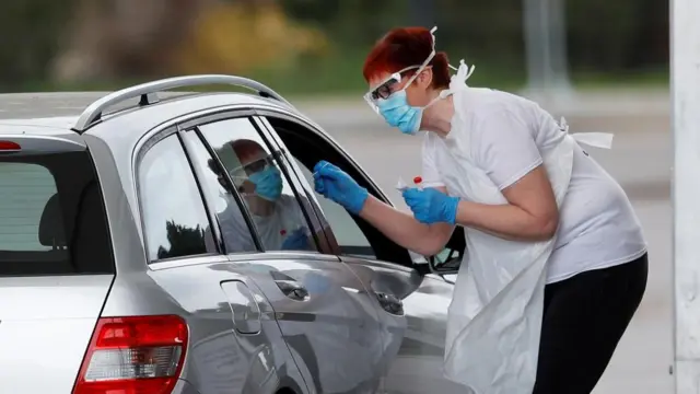 A health worker tests a person in a car at a drive-in testing centre, Chessington, 03 Apr 2020