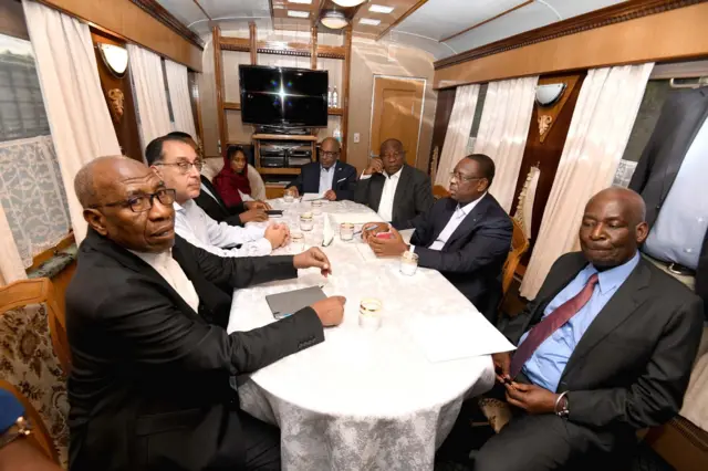 African delegation sit around table in train carraige